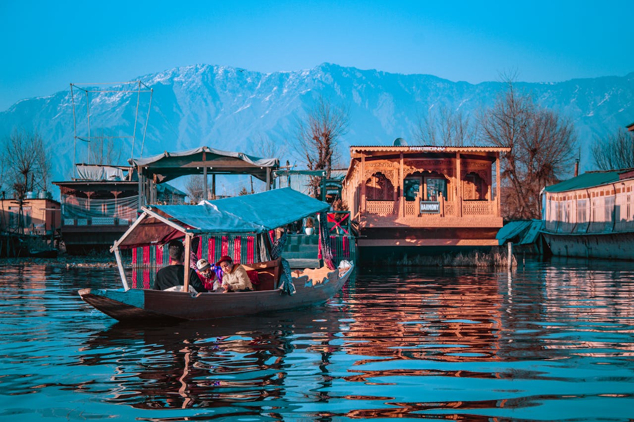 A group enjoying a serene Shikara ride on Dal Lake, with stunning mountain views in Srinagar, Kashmir.
